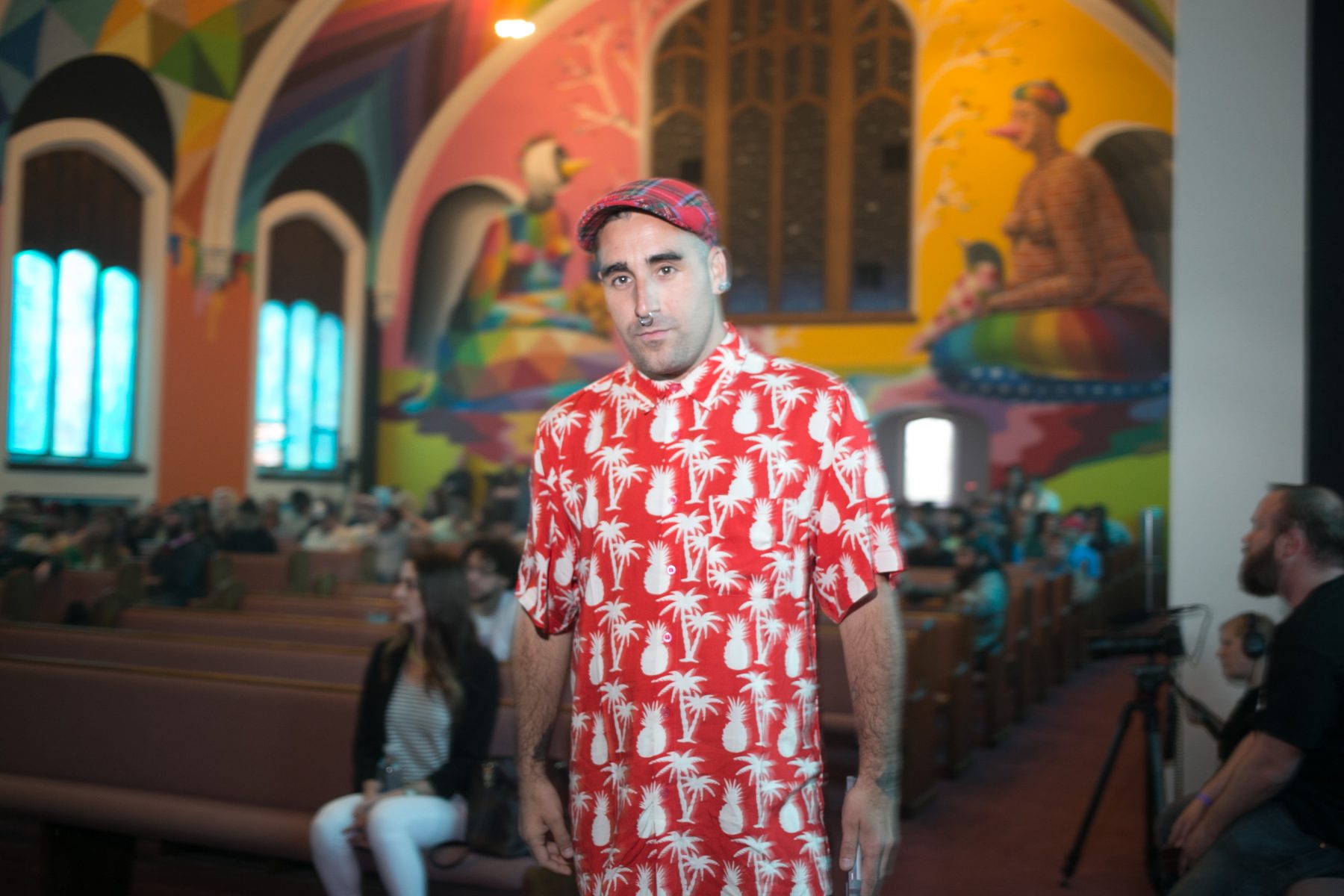 Okuda San Miguel standing under his mural at the International Church of Cannabis in Denver Colorado